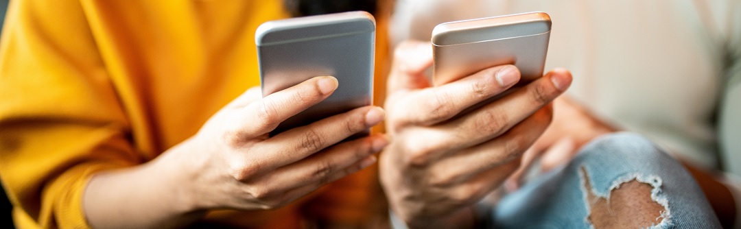 Two people each holding a cellphone. 