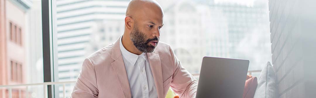 Man sitting in a bright office looking down at his laptop