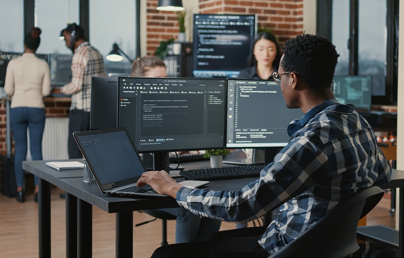 System engineer sitting at desk with multiple screens