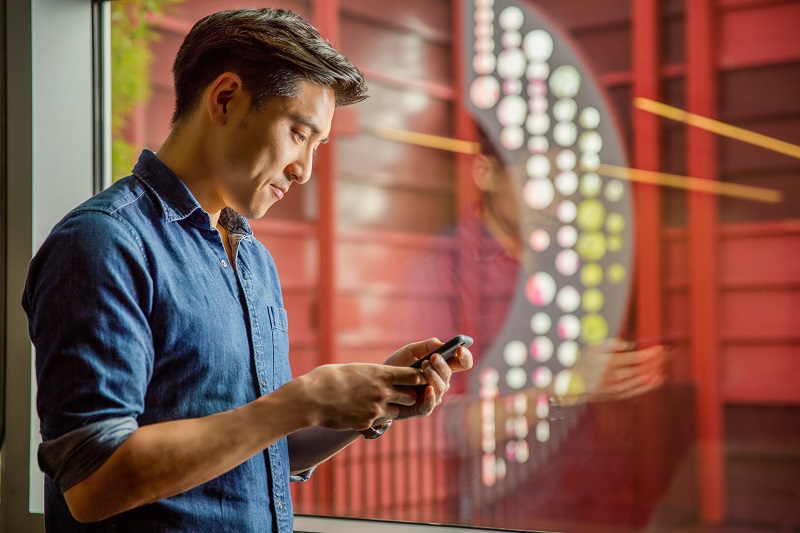 man looking at cell phone in front of colorful stairway