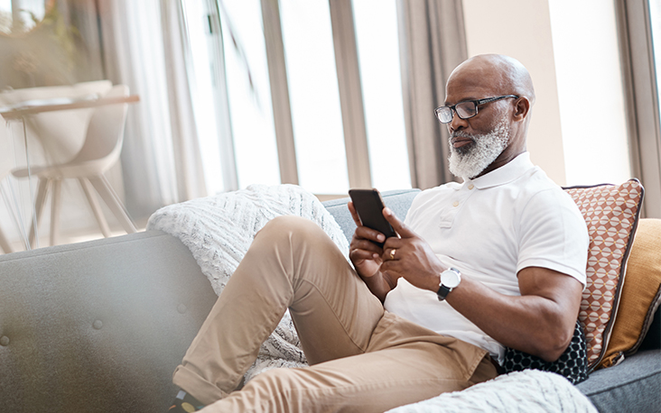 Man on a couch looking at cell phone, pondering who might be contacting him