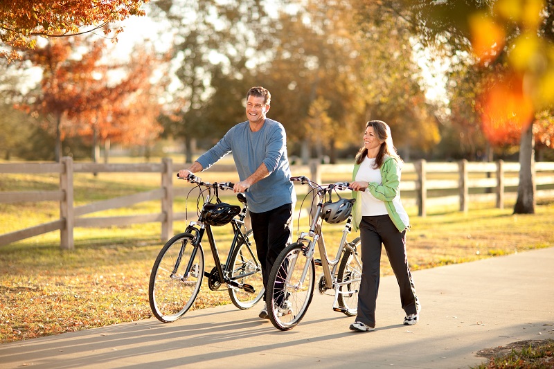 Man and woman walking bicycles down path