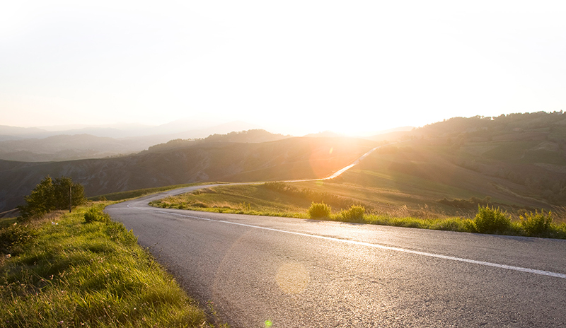 Two-lane road stretching toward sunset