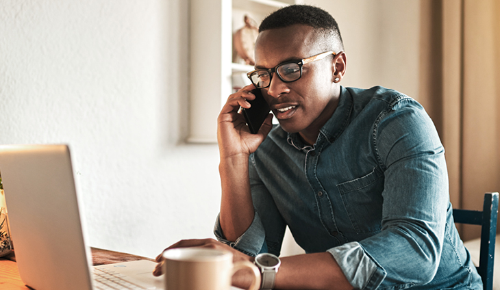 A man using a laptop while talking on the phone