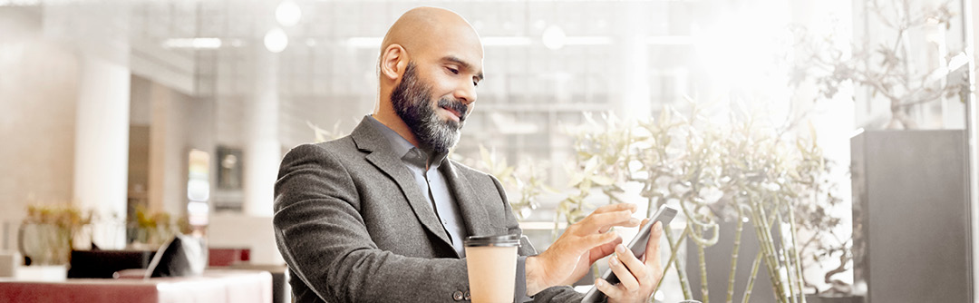 Man sitting in a well lit room at a table checking his phone