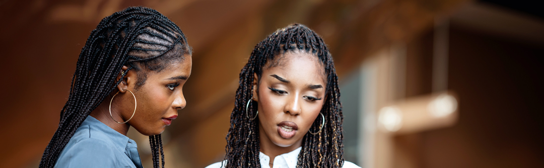 Two young women are speaking to each other in business attire