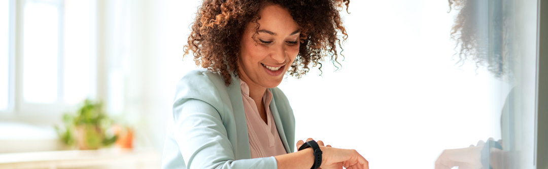 A young woman looks at her watch on her wrist